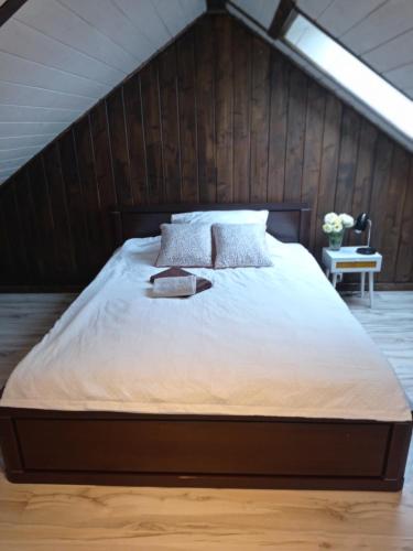 a bedroom with a large bed with a wooden wall at apartamentyDvorskie in Nowy Sącz