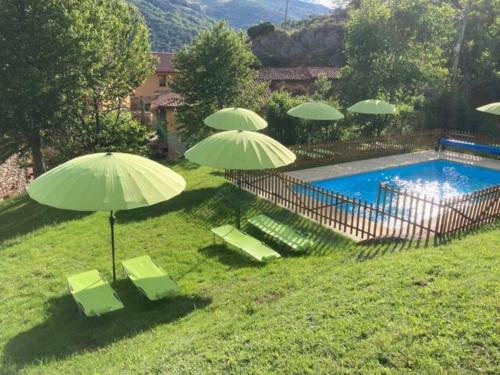 a group of green umbrellas and chairs next to a pool at El hotel de Verdiago in Verdiago