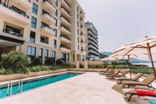 una piscina con sedie e ombrelloni accanto a un edificio di Casa Al Mare Premium Residences a Rafailovici