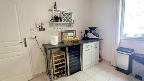 une cuisine avec un comptoir noir avec des bouteilles de vin dans l'établissement Maison 2ch, 74m², tout équipée, parking, jardin, à Saint-Julien-les-Villas