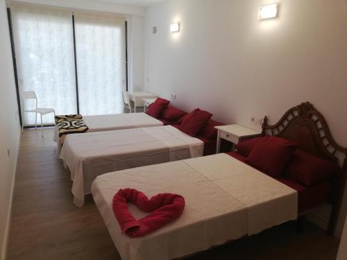 a hotel room with three beds with red pillows at Chajofe 8 in Los Cristianos