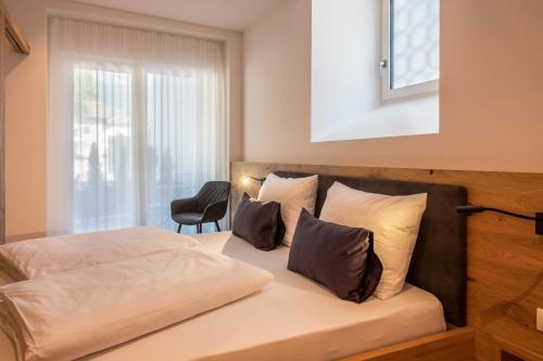 a bedroom with a bed with pillows and a window at Luisl Hof - Apartment Herbae in Cornaiano