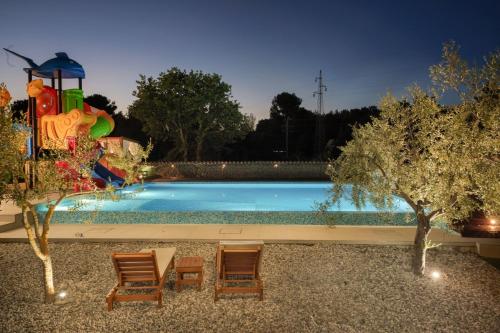 una piscina con 2 sillas y un tobogán de agua en Luxury home Alpha, pool, camp Volme - nearby Kamenjak, en Banjole