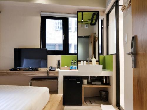 a bedroom with a bed and a desk with a television at Cho Hotel in Taipei