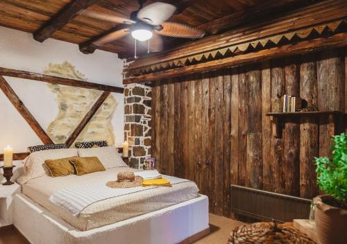 a bedroom with a bed in a room with wooden walls at Traditional house Alexis Coco with pool and fire place in Tríkorfon