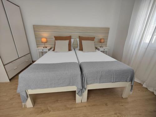 a bedroom with a large white bed with two tables at Corkoon - Duna Parque Resorts & Hotels in Vila Nova de Milfontes