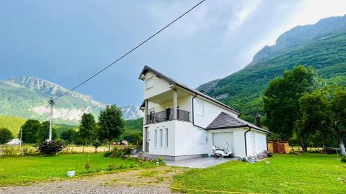 a white house in a field with mountains in the background at A Breath of Fresh Air in Gusinje