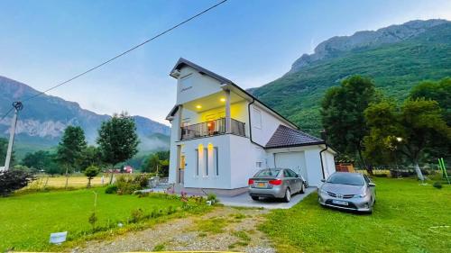 a house with two cars parked in front of it at A Breath of Fresh Air in Gusinje