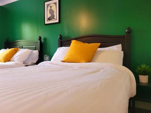 a green bedroom with two beds with yellow pillows at Motel Abricafé in Stoneham