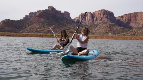 two women are sitting on kayaks in the water at Zion View Camping in Hildale