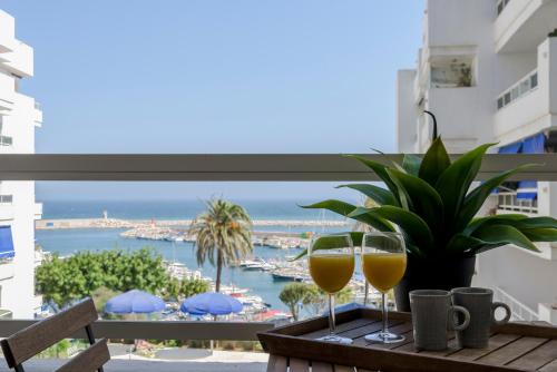 two glasses of wine on a table with a view of the ocean at Estepona Marina with Sea Views, Pool and Parking in Estepona