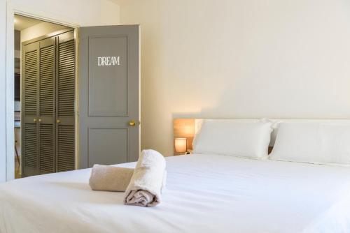 a bedroom with a white bed with a towel on it at Estepona Marina with Sea Views, Pool and Parking in Estepona