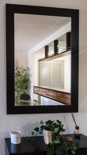 a mirror on a wall above a table with a plant at Estepona Marina with Sea Views, Pool and Parking in Estepona