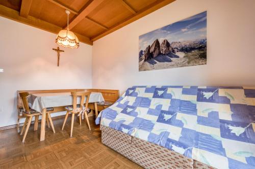 a bedroom with a bed and a table and a cross on the wall at Ciasa La Palsa App 4 in San Vigilio Di Marebbe