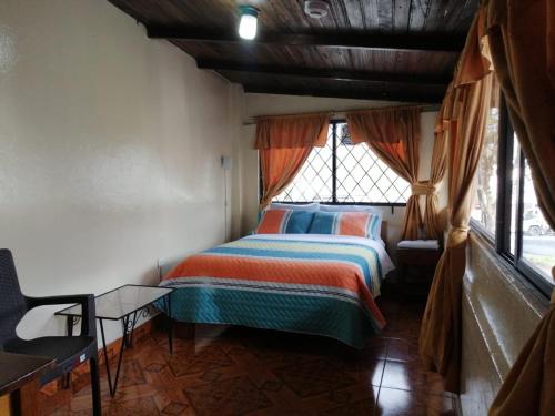 a bedroom with a bed in a room with windows at Hostal Cumbres Andinas in Ibarra
