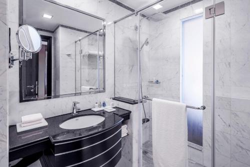 een witte badkamer met een wastafel en een douche bij Radisson Blu Hotel, Dubai Media City in Dubai