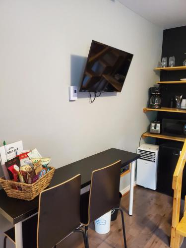 a black table with chairs and a television on a wall at Motel Abricafé in Stoneham