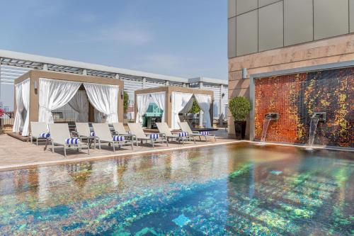 a large swimming pool with chairs and a building at Radisson Blu Hotel, Dubai Media City in Dubai