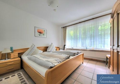 a bedroom with a bed and a large window at Friesenhain Ferienwohnungen in Sankt Peter-Ording