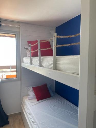 - une chambre avec 2 lits superposés et des oreillers rouges dans l'établissement Appt T1 bis, terrasse face mer, rénové, climatisé, à Port-Leucate