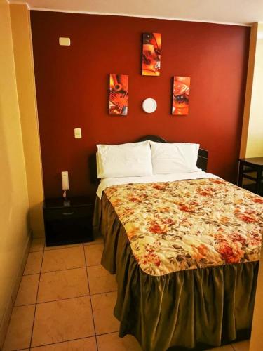 een slaapkamer met een groot bed met een rode muur bij Los Sauces in Huacho