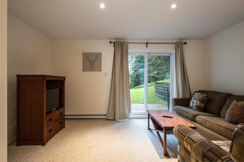 a living room with a couch and a tv at Aiglon by Rendez-Vous Mont-Tremblant in Mont-Tremblant