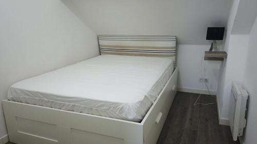 - un petit lit blanc dans une petite chambre dans l'établissement Appartement cosy à quelques mètres de la plage, à Pornichet