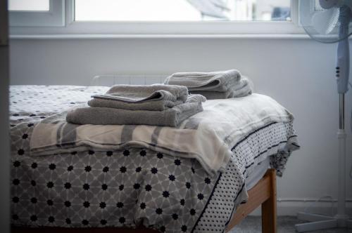 a bed with towels on top of it with a window at Harbour Court - 2 Bedroom Apartment - Saundersfoot in Saundersfoot