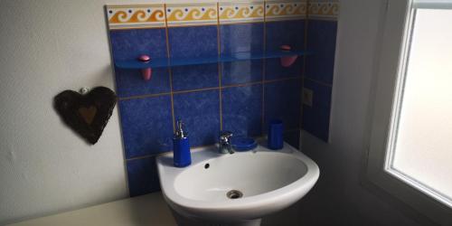 een blauw betegelde badkamer met een wastafel en een toilet bij La Cour Du Puits Chambre Victor in Cormeilles