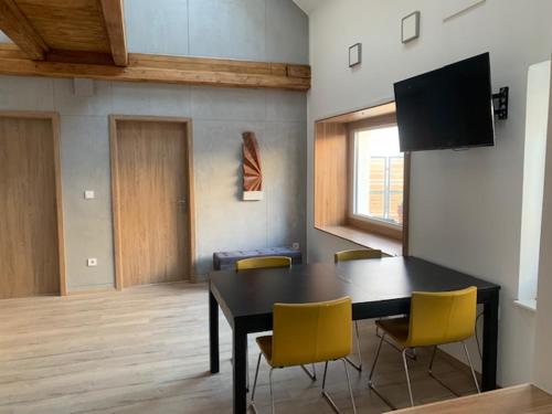 a dining room with a black table and yellow chairs at Loft Pihenő és Wellness Ház in Balatonfüred