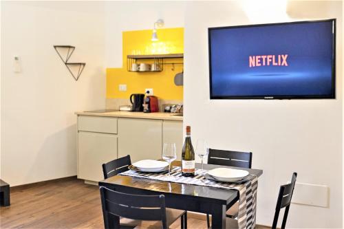 comedor con mesa y TV en la pared en Loft Orvieto Centro Storico, Wi-Fi e Netflix vicino Pozzo della Cava,"Carvajal Rooms", en Orvieto