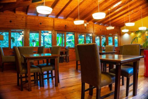uma sala de jantar com mesas, cadeiras e janelas em Selva de Laurel em Porto Iguaçu