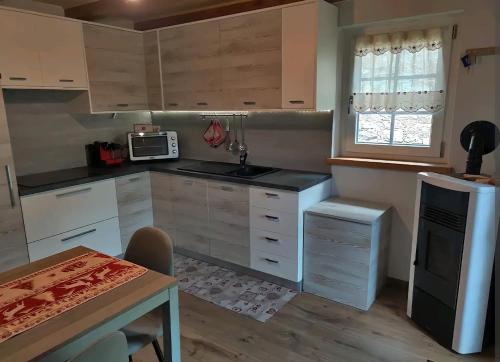 a kitchen with white cabinets and a table and a microwave at Fuchs Haus in Formazza