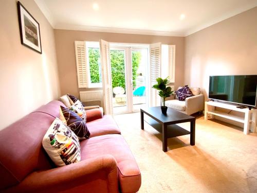 a living room with a couch and a tv at NEW! Luxury YELLOW HOUSE Bright Modern Detatched Home with PRIVATE PARKING, NETFLIX Close Luton, M1, and AIRPORT Ideal for Families, Professionals, Consultants, LONGER STAY OPTIONS in Caddington