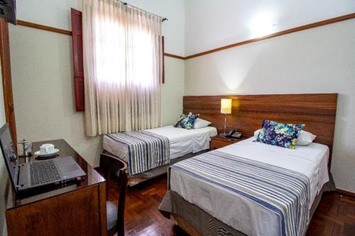 a hotel room with two beds and a laptop on a desk at Hotel Nacional Inn Araxá Previdência in Araxá