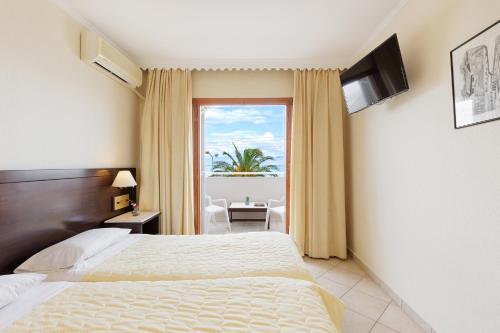 a hotel room with two beds and a window at Aphrodite Beachfront Hotel by Konnect, Roda in Roda