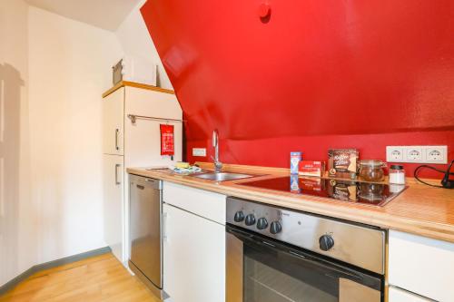 a kitchen with a stove and a red wall at Apartments im Einhornhaus in Lübeck