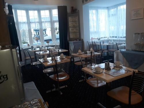 a restaurant with wooden tables and chairs and windows at Newton House in Torquay