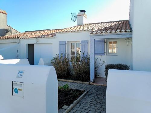 a white house with a white refrigerator in front of it at Maison pour 6 - Piscine - 750m de la plage in LʼÉpine