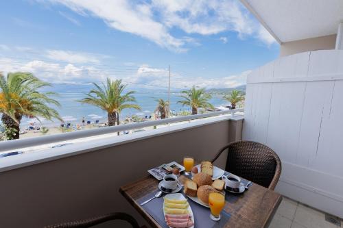 a table with food on a balcony with a view of the beach at Aphrodite Beachfront Hotel by Konnect, Roda in Roda
