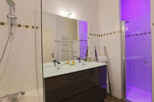 ein Badezimmer mit einem Waschbecken und einer Dusche mit lila Beleuchtung in der Unterkunft Duplex joliment décoré et sa cour ensoleillée in Saint-Martin-de-Ré