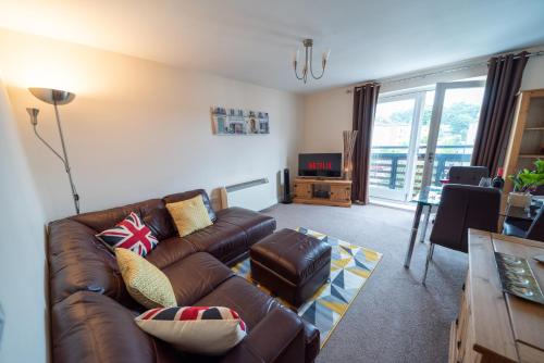 a living room with a leather couch and a television at Neptune Marina in Ipswich