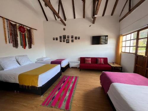 a room with three beds and a red couch at CASA CRISTOBAL Siete Cuartones in Cusco