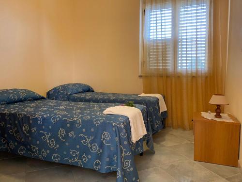 Zimmer mit 2 Betten, einem Fenster und einem Tisch in der Unterkunft La notte - capo vaticano in San Nicolò