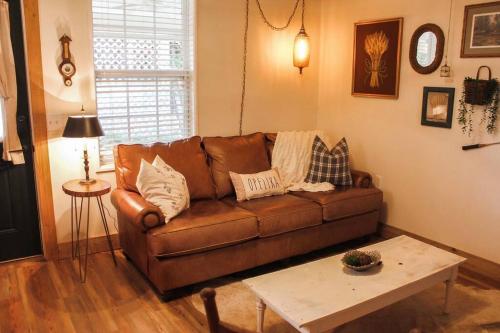 sala de estar con sofá marrón y mesa en The Greenhouse Cozy Cottage- Walk to Downtown!, en Opelika