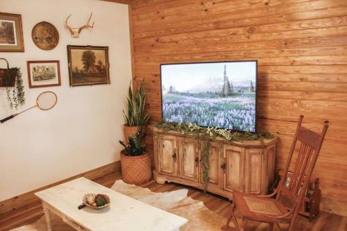 un soggiorno con TV a schermo piatto su una parete in legno di The Greenhouse Cozy Cottage- Walk to Downtown! a Opelika