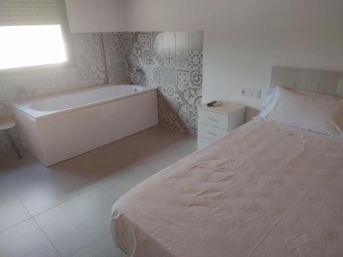 a white bedroom with a bed and a bath tub at Cal Mistero in Useras