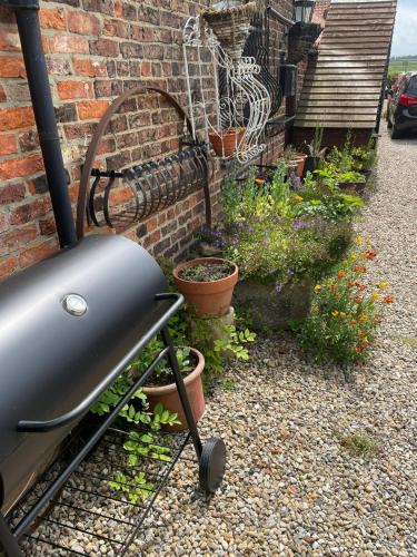 a garden with potted plants in front of a brick wall at Yarm Cottages Sleeping 6 Next to Fox Covert Pub in Kirk Leavington