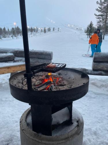 a fire pit in the snow with people in the background at Yllästölli 2 A, Äkäslompolo in Kolari