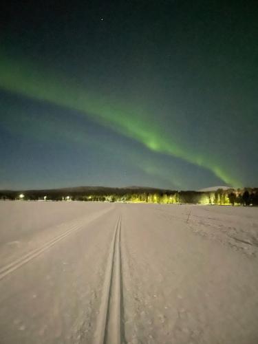 an image of the aurora in the sky over a snow covered field at Yllästölli 2 A, Äkäslompolo in Kolari
